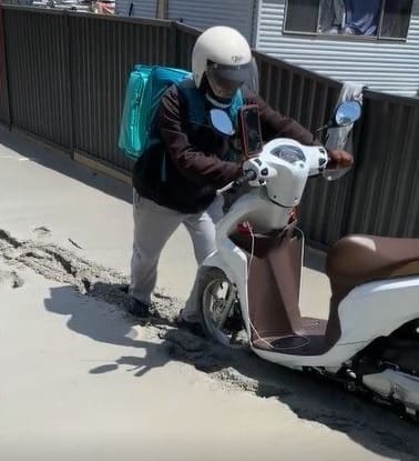 Entregador atola moto em calçada de cimento fresco e perde a paciência