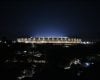 Vista panorâmica e noturna do Estádio do Mineirão totalmente iluminado sob o céu escuro.