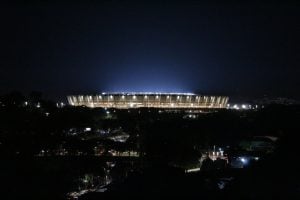 Vista panorâmica e noturna do Estádio do Mineirão totalmente iluminado sob o céu escuro.